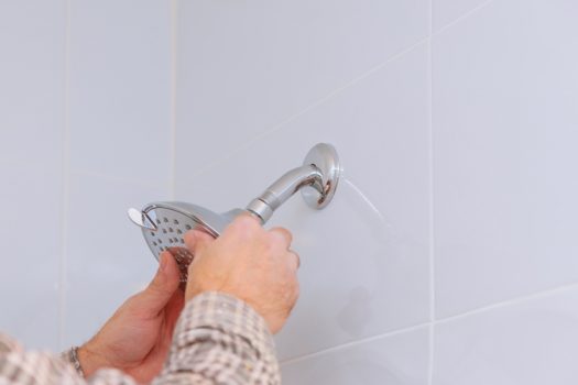 mains d'homme réparant le pommeau de douche